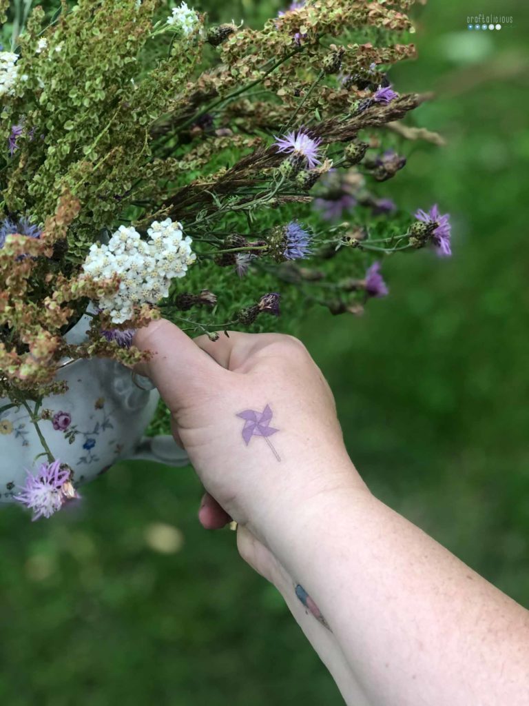 enjoying summer at home with summer flowers from the meadow in an old coffee put while wearing temporary tattoos