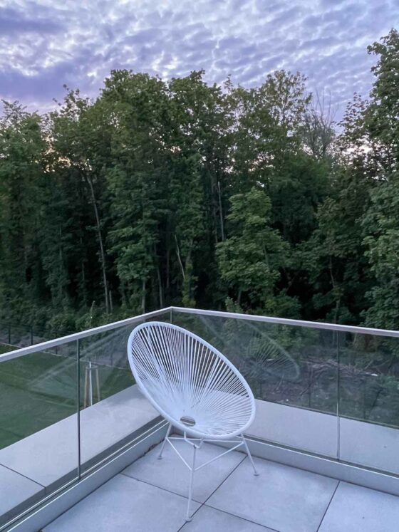 Acapulco chair on balcony overlooking forest and sunset