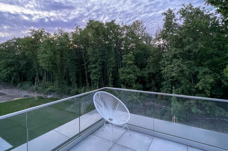 Acapulco chair on balcony overlooking forest and sunset